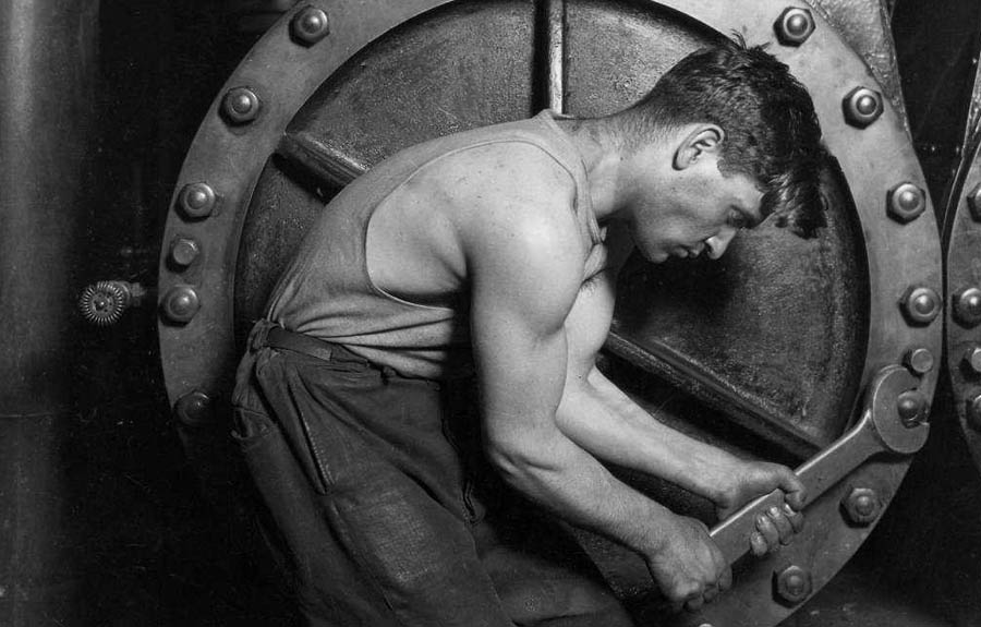 Lewis Hine photo of muscular worker tightening bolts.